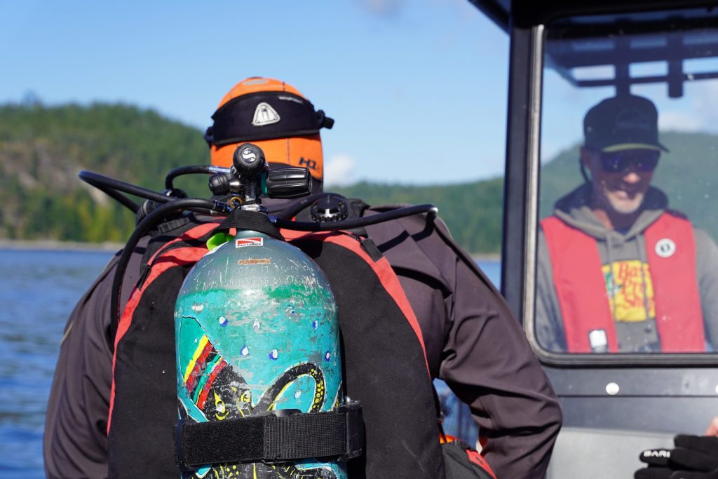 A scuba diving tour guest and its gear getting ready to drop into the campbell river waters