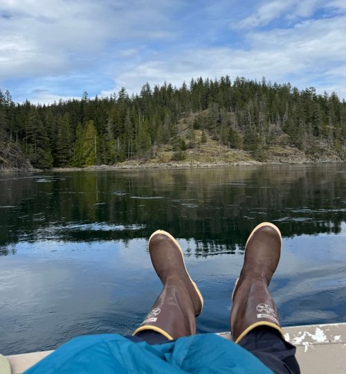 Feet dangling off the side of the boat, enjoying the view of the ocean and coastline during a guided ocean tour.